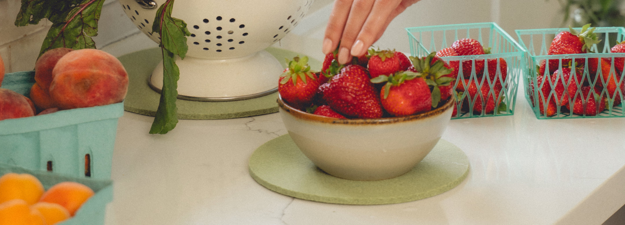 A felt cutout of a rabbit sits on a white slatted surface. A small bowl of mixed fruit, including strawberries, melon, and pineapple, is placed nearby.