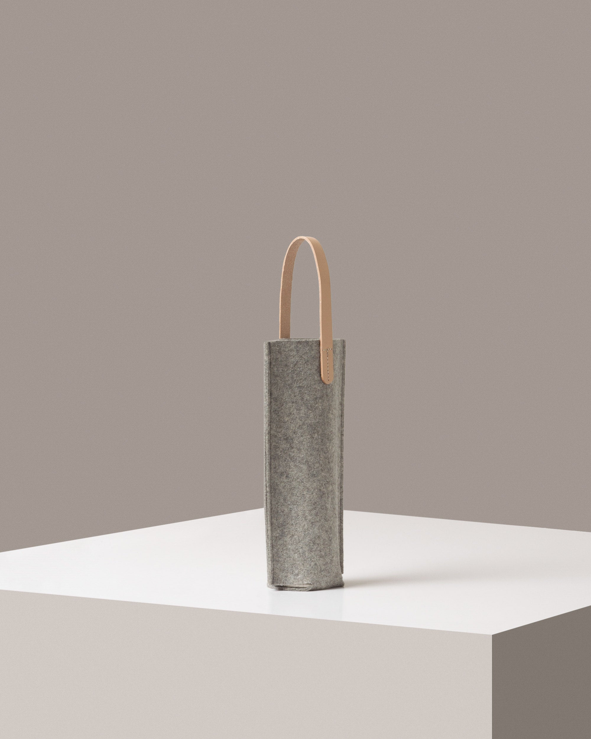 A light grey Hana Merino Wool Bottle Bag on a white base displayed in a side-view