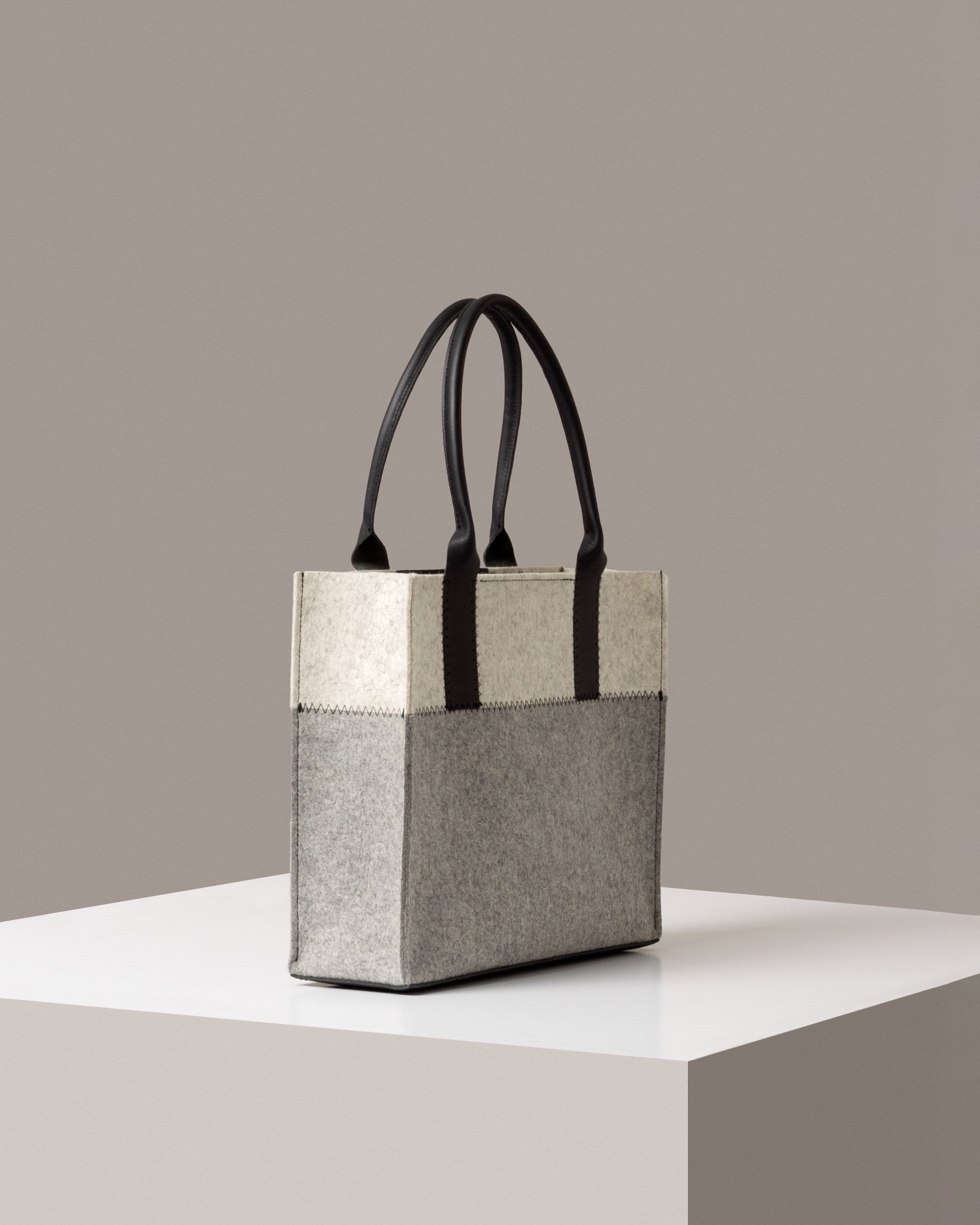 A Jaunt Midi Merino Wool Felt Tote by Graf Lantz in white, gray, and black colors on a white base displayed in a side-view
