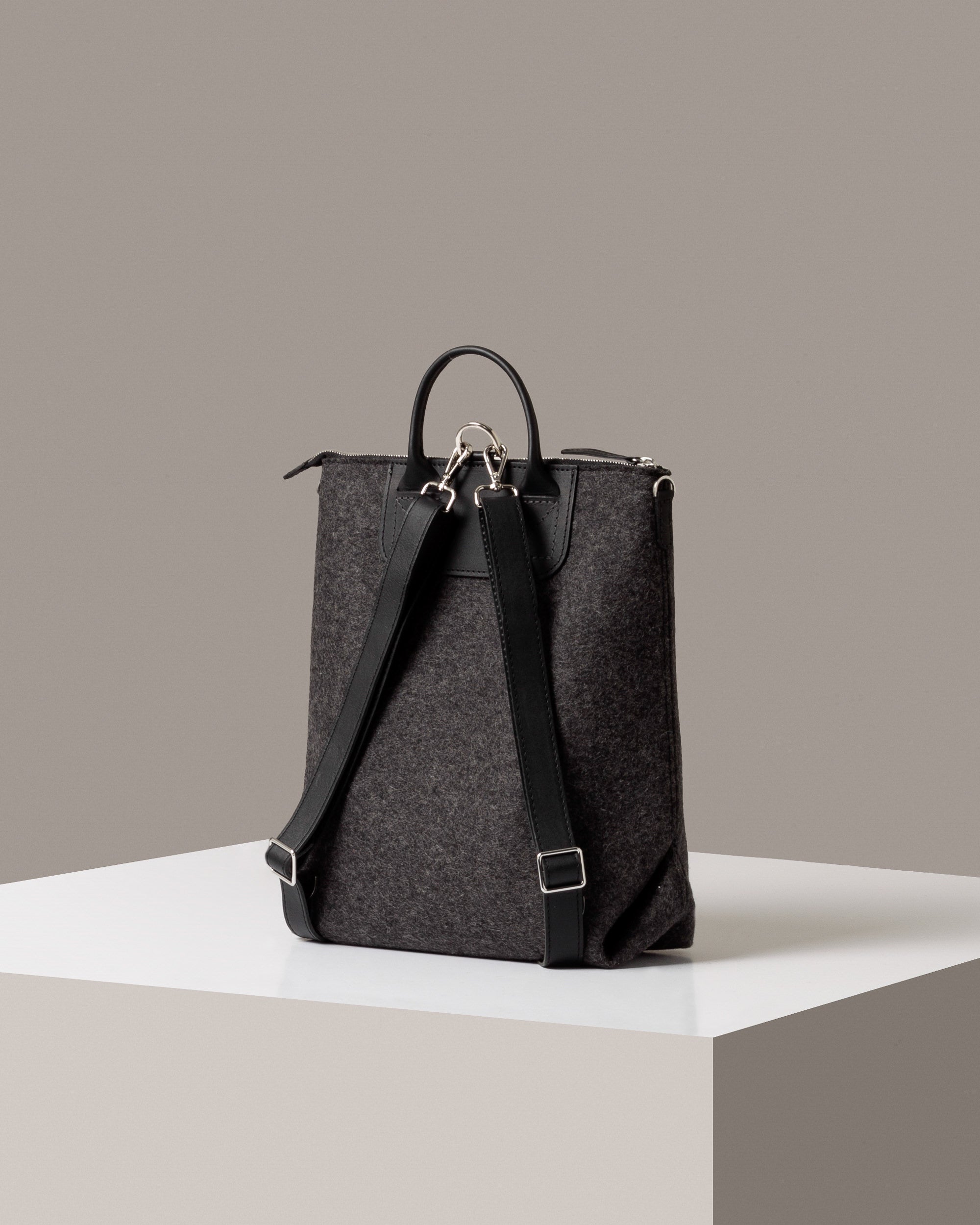Rear view of a dark gray Bedford Merino Wool Felt Backpack by Graf Lantz featuring black shoulder straps