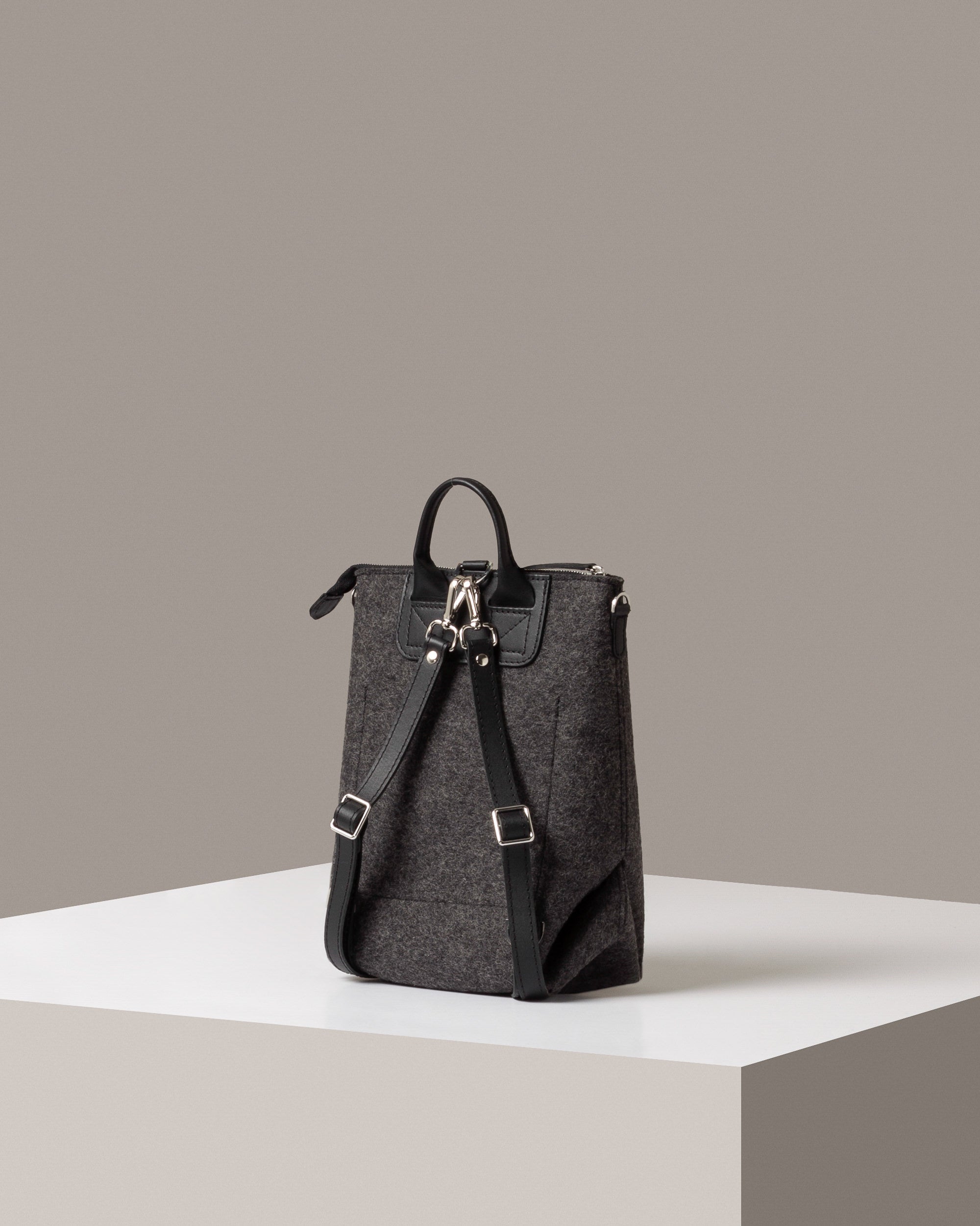 Rear view of a charcoal-colored Bedford Merino Wool Felt Backpack by Graf Lantz featuring black leather shoulder straps