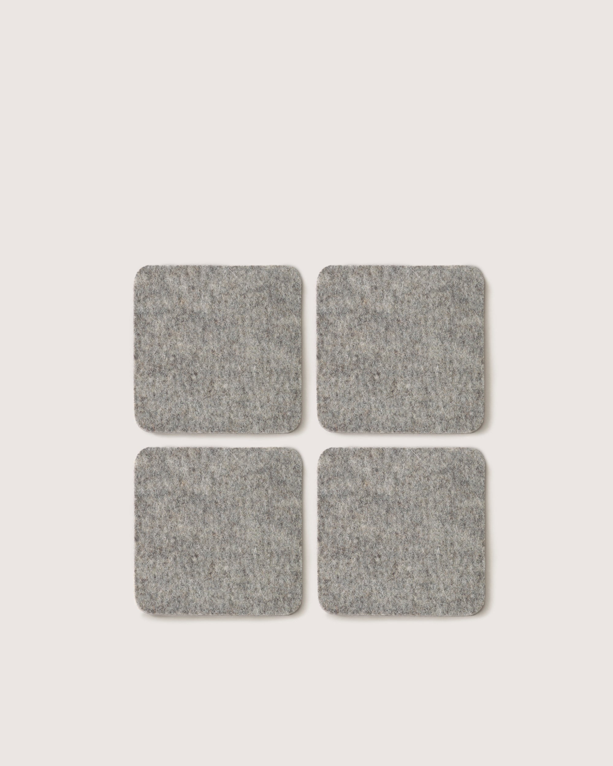 Four graf lantz square gray felt pads crafted from German Merino wool are positioned in a 2x2 grid on a simple white background.