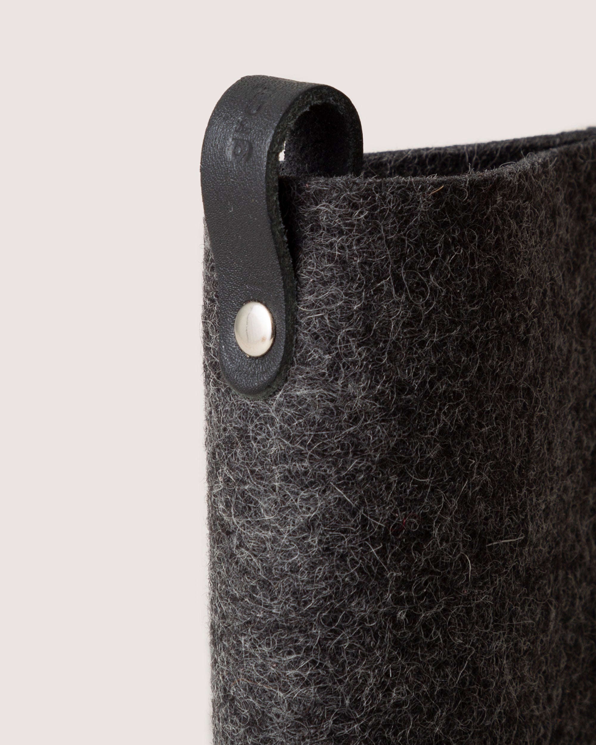 Close-up of a graf lantz gray felt eyeglass sleeve crafted from Merino wool, featuring a black leather strap with a silver rivet. The strap curves and extends from the top edge, offering both softness and functionality against a plain, neutral background.