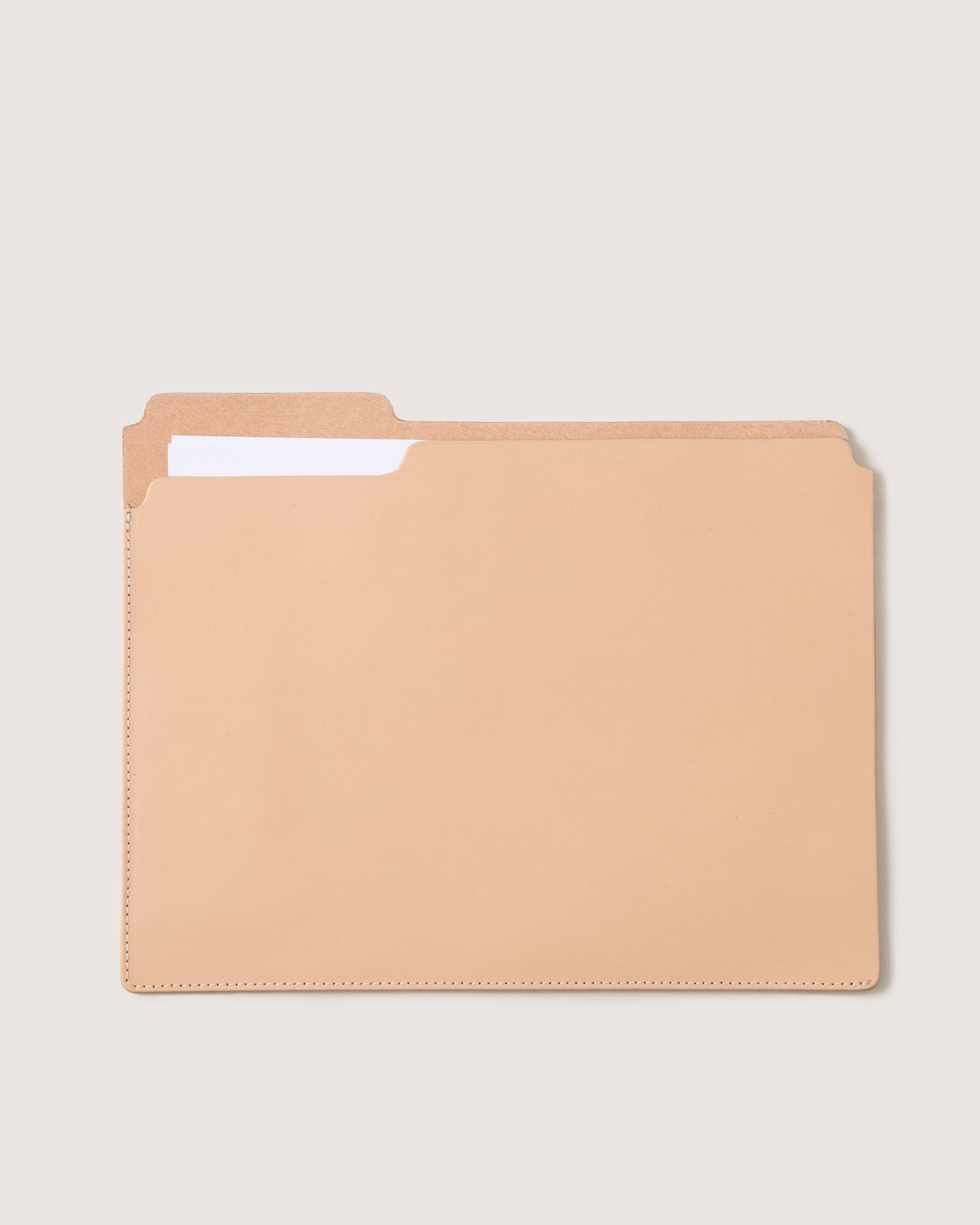 A plain manila file folder with a top tab, from the brand graf lantz, is partially open to reveal a single white sheet inside. Its minimalist design is enhanced by the light beige background.