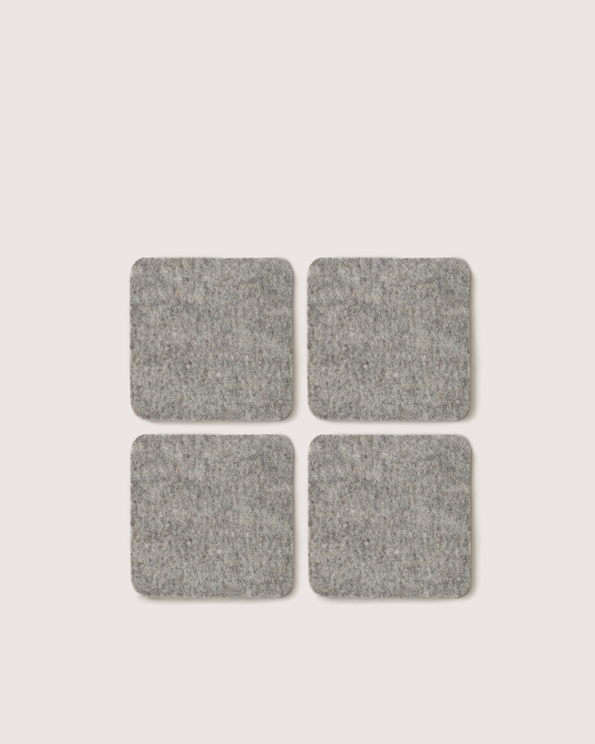 Four graf lantz square gray felt pads crafted from German Merino wool are positioned in a 2x2 grid on a simple white background.
