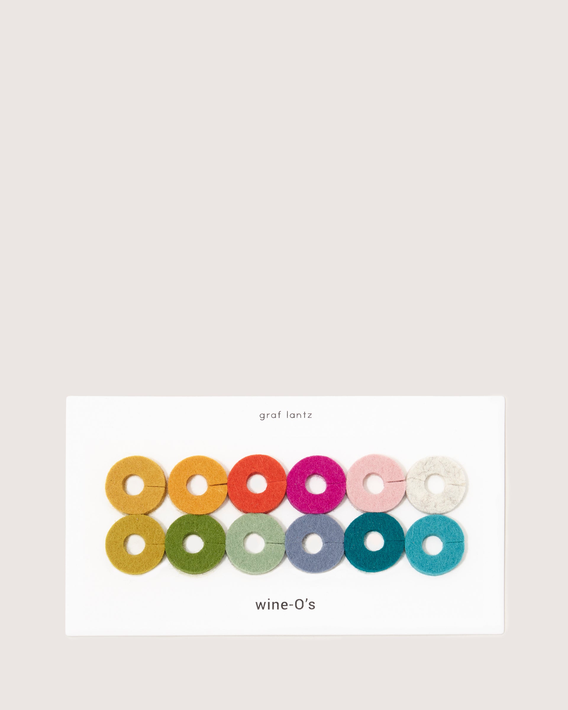 Introducing graf lantzs Wine-Os: a vibrant set of twelve sustainable wool wine glass markers in unique colors. Elegantly displayed on an eye-catching card, these charming markers add a splash of color and personality to any gathering.