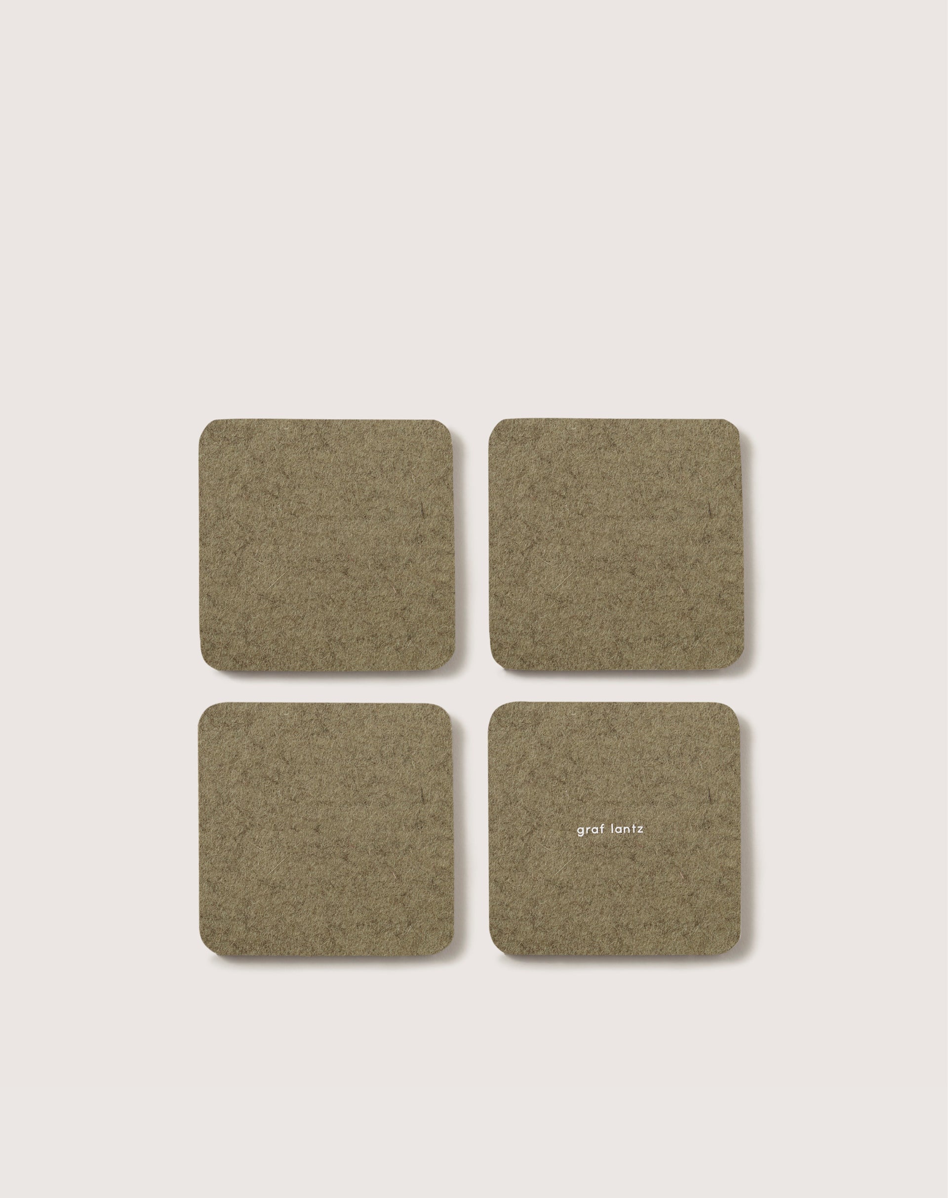 A set of four square olive green Bierfilzl coasters by graf lantz, crafted from German Merino wool, are displayed in a 2x2 grid on a light background. One coaster features small white text.