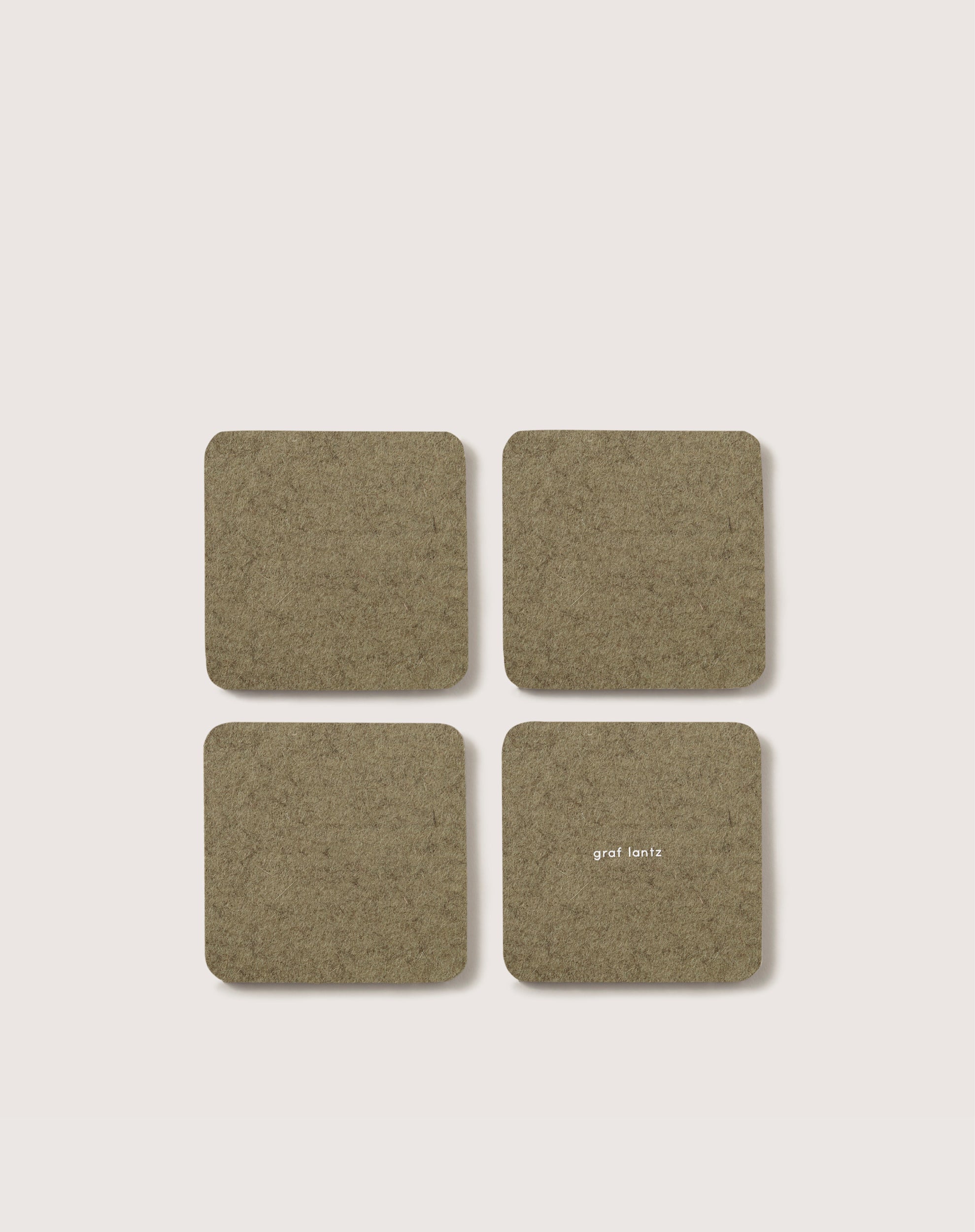 A set of four square olive green Bierfilzl coasters by graf lantz, crafted from German Merino wool, are displayed in a 2x2 grid on a light background. One coaster features small white text.