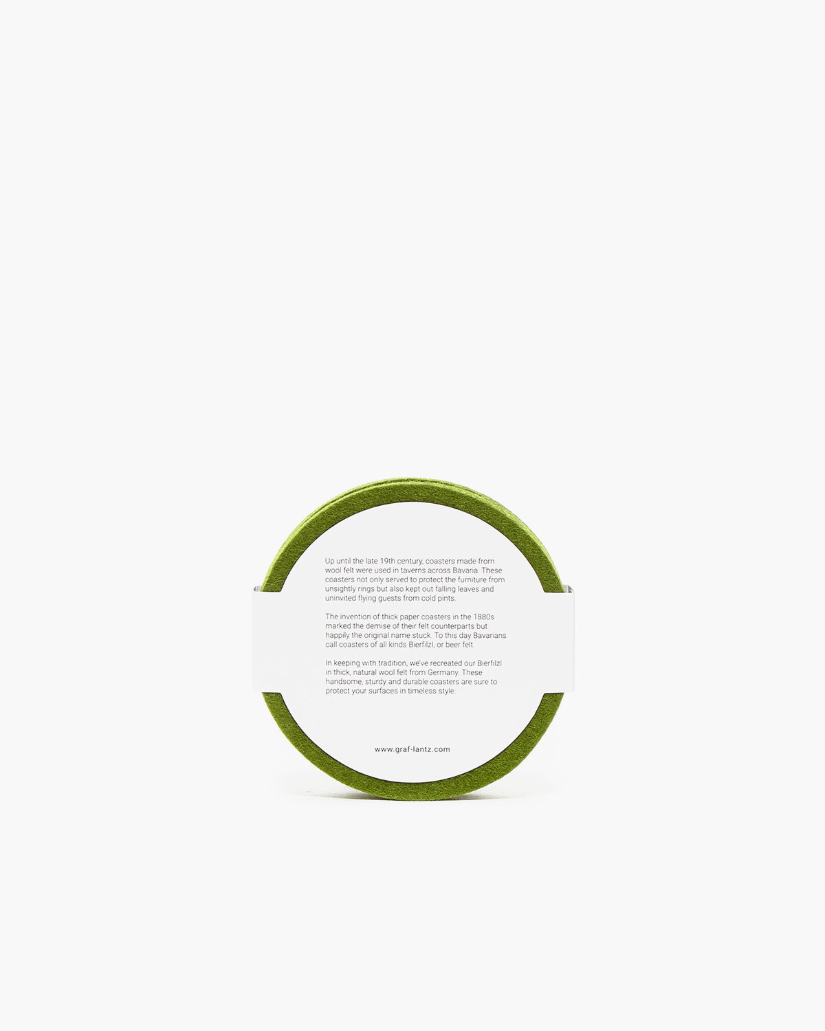 A green circular object from graf lantz, akin to a coaster, bears a white paper label wrapped around it. Mystery shrouds its purpose due to partially legible text. Set against a plain white background, the item sparks curiosity and intrigue.